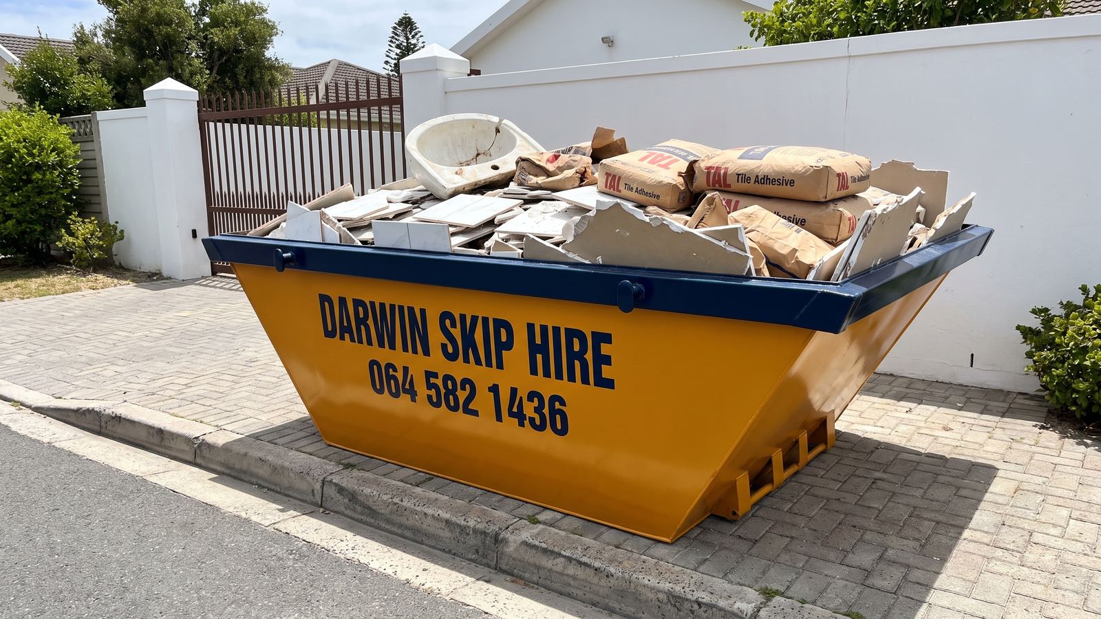 Darwin 2m³ mini skip holding broken bathroom tiles, a basin and adhesive bags.