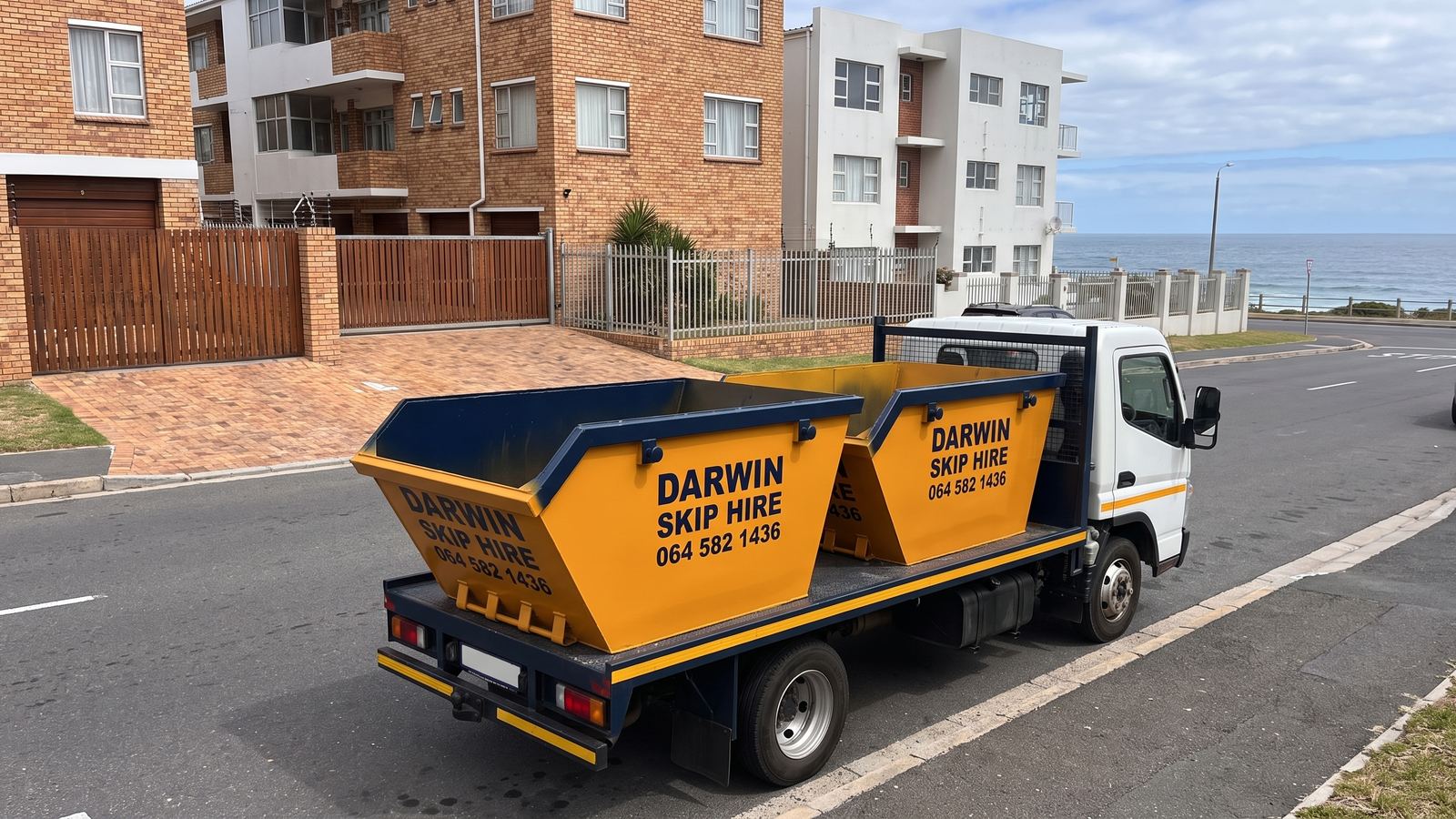 White skip-loader truck carrying two amber Darwin Skip Hire mini skips.